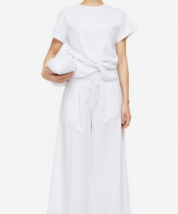 Photograph of a young asian woman in a white loose fitting t shirt and matching pants holding a folded white cloth