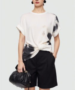 Photograph of a young asian woman in a white tie dye shirt black high waisted shorts black handbag and black earrings