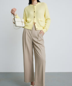 Photograph of a young asian woman with straight black hair wearing a yellow cardigan beige trousers white shoes and handbag