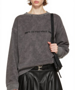 Photograph of a young woman in a gray sweater black leather skirt and sunglasses holding a black shoulder bag