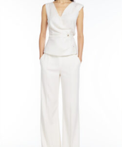 Photograph of a young woman in a sleeveless white wrap top and wide legged white pants against a plain white background