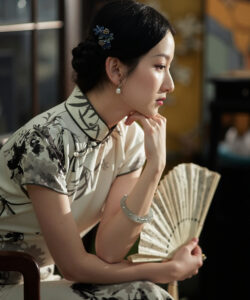 Photograph of an asian woman in a floral cheongsam holding a fan with a floral hairpiece elegant indoors