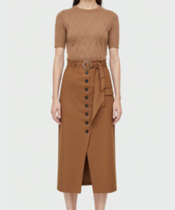 Photograph of an east asian woman in a brown quilted top and matching high waisted skirt with black buttons