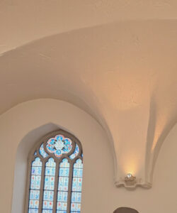 Photograph-of-an-elegant-cream-colored-arched-ceiling-with-ornate-blue-tinted-stained-glass-windows-showcasing-gothic-architectural-design