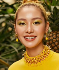 Asian Woman With Blonde Hair In A Bun Wearing Vibrant Yellow Makeup And A