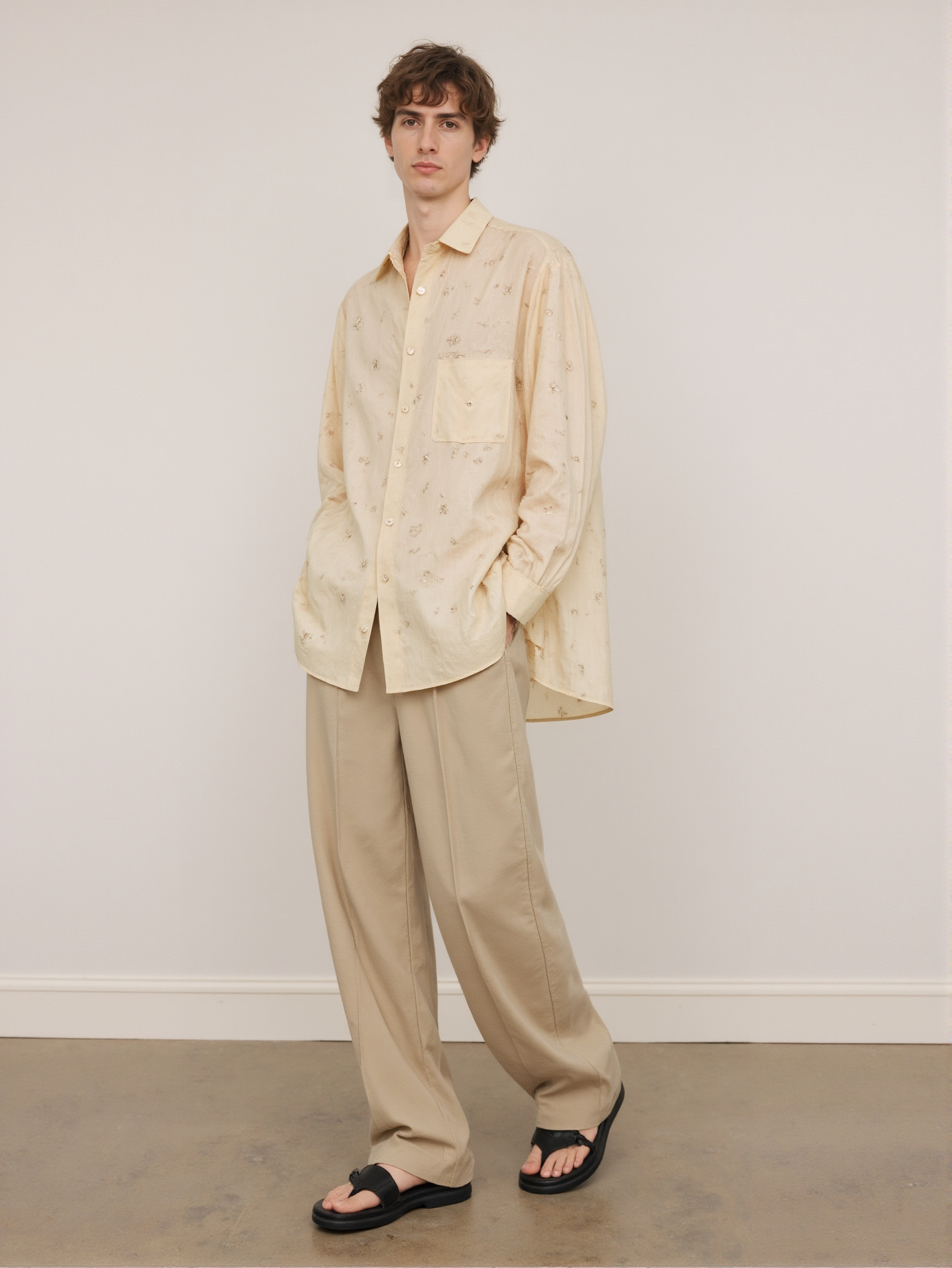 Caucasian Man In Beige Shirt And Pants Black Sandals Standing Against Plain