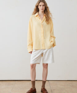 A Slender Light Skinned Woman With Long Wavy Wavy Blonde Hair In A Yellow Shirt And