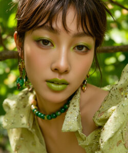 An Asian Woman With Green Makeup Green Green Lipstick And A Green Beaded Necklace