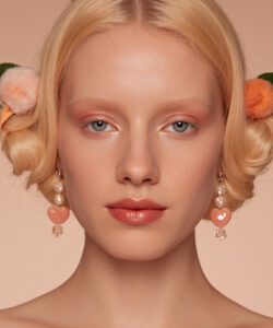 Fair Skinned Blonde Woman With Curls Wearing Wearing A Pearl Tiara Peach Earrings And 1