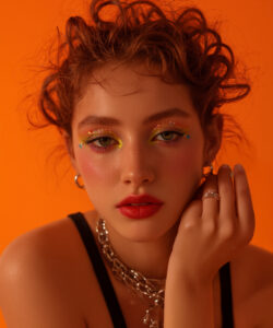 Fair Skinned Woman With Curly Red Hair Colorful Eye Makeup Red Lips And A Black Tank
