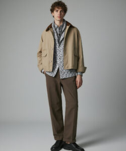 Haired Man In A Beige Jacket Patterned Patterned Shirt Brown Pants And Black Shoes