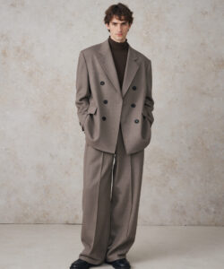 Haired Man In A Grey Double Breasted Suit Black Turtleneck And Black Shoes Against