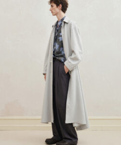 Haired Man In A Long Light Grey Coat Dark Pants And Floral Shirt Standing