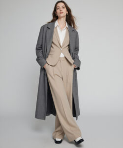 Light Skinned Woman In A Gray Coat Coat Beige Suit And White Blouse Standing