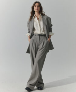 Light Skinned Woman With Wavy Brown Hair Wearing A Grey Suit White Blouse And