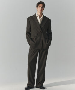 Man In A Dark Pinstripe Suit White Shirt And Black Shoes Standing Against A