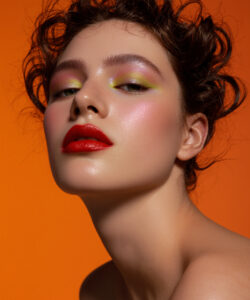 Skinned Woman With Curly Brown Hair Red Lipstick And Colorful Eyeshadow Set Against An
