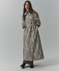 Skinned Woman With Long Brown Hair Wearing A Textured Knee Length Gray Coat Against