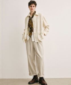 White Man With Curly Hair Wearing Beige Striped Jacket Patterned Scarf White Shirt And