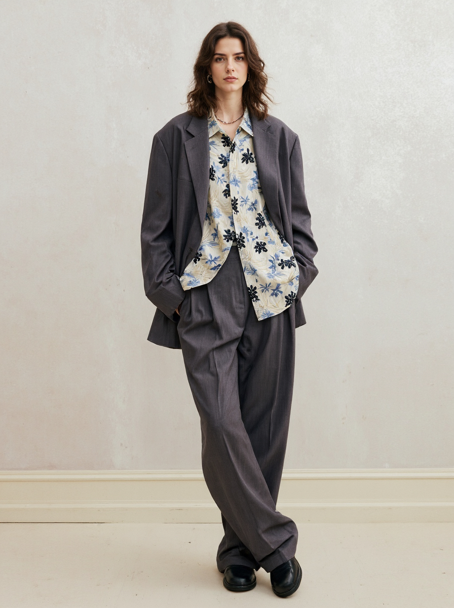 Woman With Wavy Hair Wearing A Gray Suit Floral Blouse Pearl Necklace Standing Against