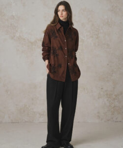 Young Woman With Long Brown Hair Wearing A Brown Floral Shirt Black Pants And